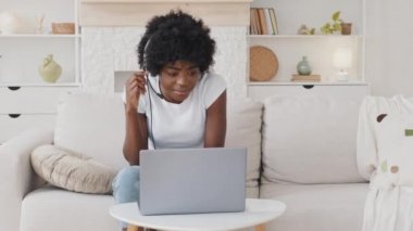 Mutlu Afrikalı Amerikalı genç kadın konferans çağrısı ile iletişim kuran kulaklık takıyor. Evde dizüstü bilgisayara bakıyor, webcam uzaklık dil kursu sınıfında bilgisayar eğitimi kavramı ile görüntülü sohbet ediyor.