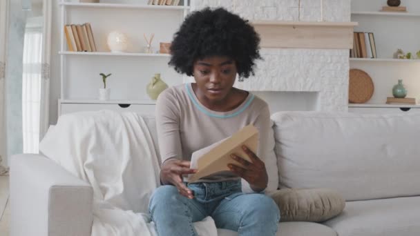 Afrikkalainen nainen avaa kirjekuoren vie paperi, lukeminen ilmoitus tuntuu turhautunut ja järkyttynyt crumples kirje. Huonoja uutisia: posti, taloudelliset ongelmat, pankkilaina, korkeat laskut, haaste, häätö. — kuvapankkivideo