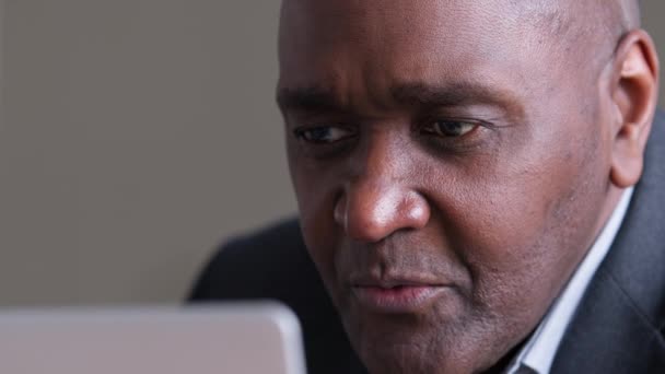 Close-up male wrinkled face african business man afro black ethnic boss manager elderly owner looking at laptop screen working online reading news receiving notification surprised opens wide eyes — Stock Video