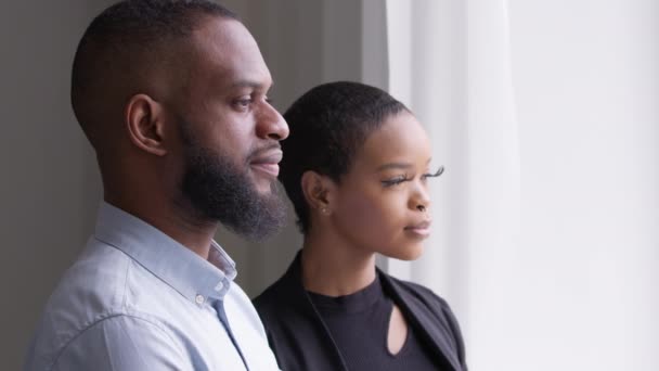 Africano casado pareja colegas negro mujer de negocios con largo pestañas y étnico hombre de negocios de pie juntos en oficina habitación mirando por ventana pensamiento contemplando soñar sentir calma armonía — Vídeos de Stock