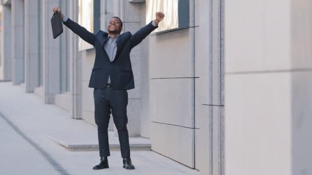 Feliz joven empresario divertido bailando solo al aire libre celebrando el viernes, logro de trabajo éxito profesional, recompensa o promoción, emocionado empleado afroamericano masculino disfrutar de danza victoria en la calle — Vídeo de stock