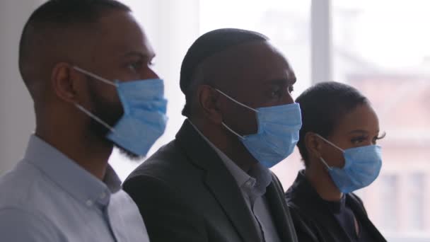 Retrato afro grupo de personas americano equipo de negocios socios de diferentes edades dos hombres negros africanos y una mujer étnica con máscaras médicas protectoras en las caras sentados en la oficina pandemia de trabajo — Vídeos de Stock