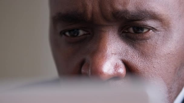 Крупним планом чоловічі очі дивляться невпізнаваний афроамериканський зрілий бізнесмен літній чоловік стикається зі зморшками, дивлячись на екран ноутбука, читаючи погані новини, що працюють за комп'ютером, насолоджуючись хорошим зором — стокове відео