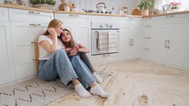 Caucasian family adult mature mother talking conversation with daughter teenager girl child sitting on floor in home kitchen holding hands chatting spending time together having rest sharing secrets — Αρχείο Βίντεο