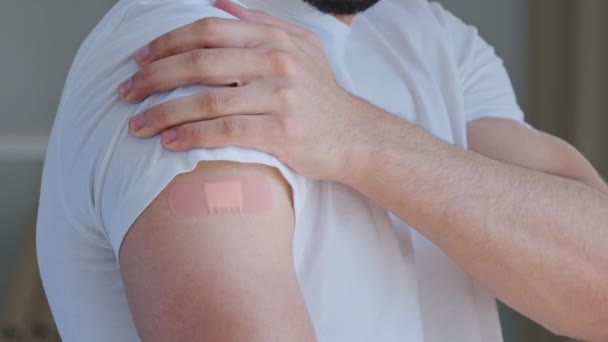 Cropped shooting arabian young man, portrait male Spaniard ethnic guy patient looking at shoulder with medical plaster on mark of injection smiling satisfied vaccination immunization against covid — Stok video