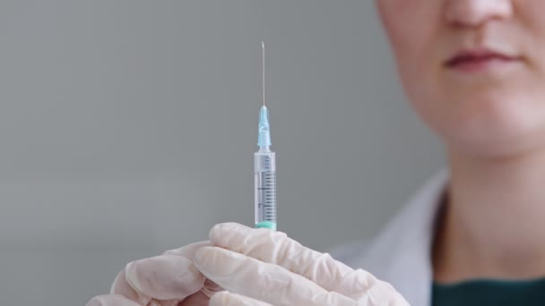 Unrecognizable woman doctor nurse medical worker scientist wears latex gloves holds syringe with needle in hands splashes of liquid antibiotic medicine injection vaccination with coronavirus vaccine — Stock Video