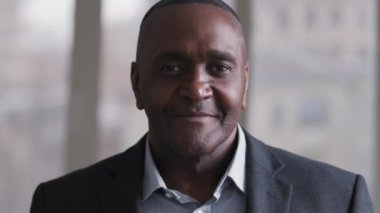 Portrait successful 50s business man mature african american ethnic black boss afro leader lawyer stands indoors in office wears formal suit looking at camera smiling toothy, male face with wrinkles