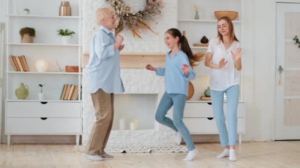 Little adorable daughter laughing jumping between mother and grandmother. Three generations woman old grandma, young woman and child granddaughter feel happy at home. Multigenerational family portrait — Αρχείο Βίντεο