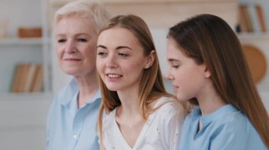 Close-up profile faces view diverse generation of women standing in row indoor smiling talking to each other. Parents and offspring, multi-generational family relatives, heredity genes, time concept