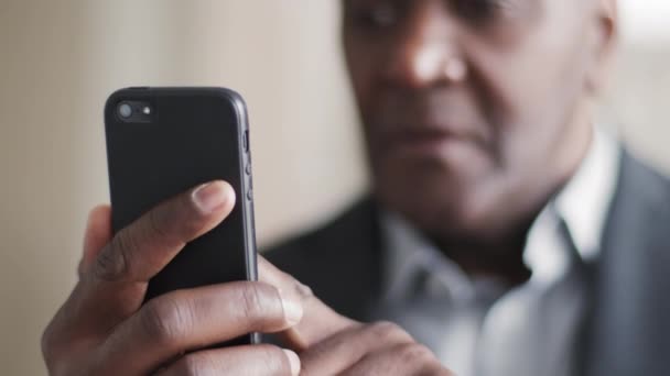 携帯電話を保持するクローズアップ男性の手、アフリカの成熟した高齢者のビジネスマンアフロ雇用者は、ネット上のショッピングオンラインチャットを注文するために現代のスマートフォンを使用して携帯電話番号の閲覧、高齢者や技術を入力します — ストック動画