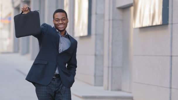 Emocionado joven afroamericano empleado hombre celebrando el éxito empresarial, promoción logro profesional o recompensa, raza negra millennial estudiante gerente empresario bailando solo en la calle al aire libre — Vídeos de Stock