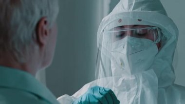 Portrait scientist in laboratory doctor nurse woman wearing medical protective uniform clothing using equipment for doing coronavirus swab Covid-19 pcr test to female old lady patient during pandemic