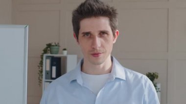 Yakın plan erkek yüzü, beyaz portre, bin yıllık iş adamı girişimci patron yatırımcı, başarılı serbest girişimci CEO kapalı alanda kameraya gülümseyen dişlere bakıyor.