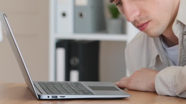 Sad tired sleepy caucasian millennial man office worker lays head on laptop keyboard falling asleep napping from exhaustion overworked stress boredom needs rest loss of energy close eyes male face — Stock Video