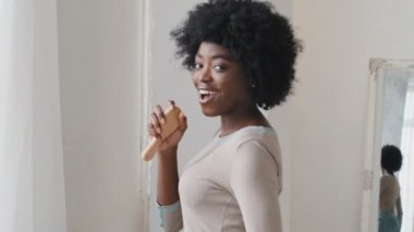 Young attractive African American millennial woman dancing singing favorite song listen music on digital playlist enjoy carefree home weekend alone. Hobby, modern tech, stress-free lifestyle concept