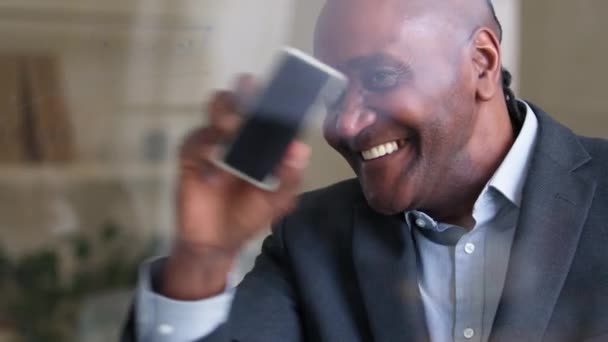 Heureux homme d'affaires africain des années 50 souriant toothy mature plus âgé professeur afro américain mâle tuteur scientifique essuie transparent panneau mur de verre avec brosse éponge dans la salle de bureau se prépare à écrire pour la leçon — Video