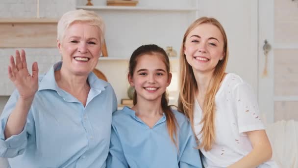 Feliz familia de tres generaciones hija abuela sentada en el sofá mira a la vista de la pantalla de la cámara web del ordenador, hace video llamada manos muestran pulgares hacia arriba la comunicación con los familiares en línea — Vídeo de stock