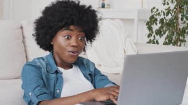 Headshot excited amazed millennial African American woman looking at laptop screen, reading email with good news. Young biracial girl feels happy surprised by unbelievable success, winner notification