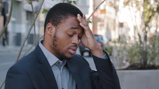 Estressado exausto jovem mestiço empregado da empresa ter sentimentos dolorosos na cabeça devido ao excesso de trabalho do computador ou sedentário estilo de vida de trabalho. Cansado homem negro, homem de negócios sobrecarregado com tarefas ao ar livre — Vídeo de Stock