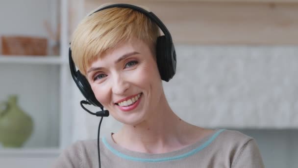 Smiling young woman wear headset conference video calling looking at laptop computer at home office, communicating in distance remote chat job interview or language course class with online teacher — Stockvideo