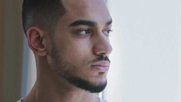 Porträtt av arabiska unga vuxna etniska man brunett spanjor kille manligt huvud ansikte tittar ut genom fönstret med allvarliga oroliga sorgliga uttryck oro om karantän isolering tänka på att lösa problem — Stockvideo