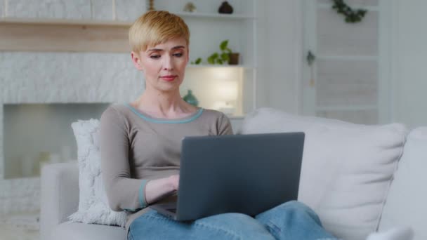 Zmęczona młoda kobieta siedzieć na przytulnej kanapie w salonie zamyka laptopa po długim użyciu. Uśmiechnięty dziennikarz niezależny bierze głęboki oddech zadowolony z wykonanego zadania, artykułu pisanego lub powieści poetyckiej — Wideo stockowe