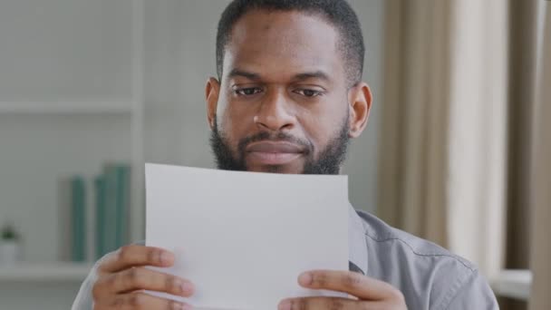 Unhappy young African guy received bad news, irritated by mistake, feeling stressed about dismissal notice. Angry black businessman opening envelope, reading banking credit loan refusal notification — Wideo stockowe