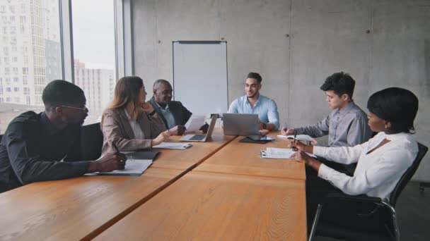 Equipo de negocios multiétnicos Empresarios multirraciales grupo de trabajadores emprendedores sentados a la mesa en reunión sesión informativa lluvia de ideas conferencia escritura en cuadernos escuchando jefe hispano con computadora portátil — Vídeos de Stock