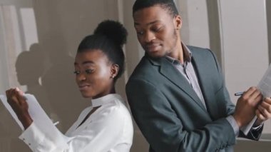 Genç Afrikalı Amerikalı öğrencilerin stajyerleri ya da çeşitli iş ortakları ofiste geri çekilip takım oluşturma etkinliği, arama çözümleri ve sinerji konseptini içeren kağıt belgeleri hazırlıyorlar.