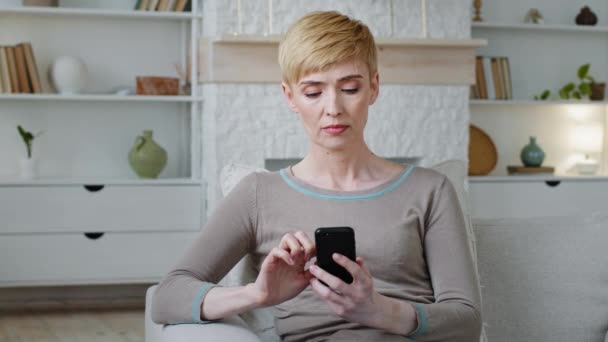 Jeune femme sérieuse utilisant des applications de téléphonie mobile, des informations de navigation sur le Web, la lecture de nouvelles SMS désagréables, mauvais message. Femme indignée impliquée dans les achats en ligne se plaindre sur l'appareil Internet lent — Video