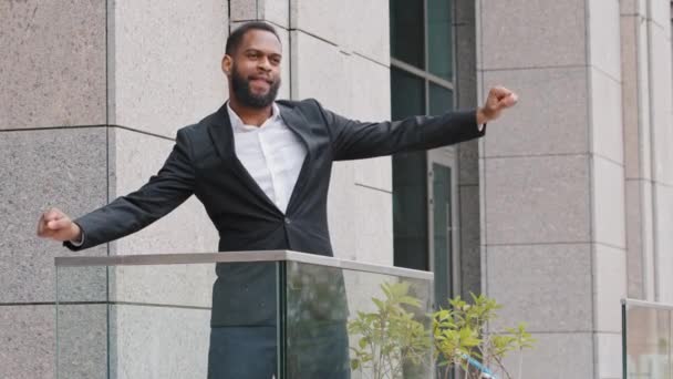 Ενθουσιασμένος νεαρός Αφρικανός εργάτης που στέκεται στο μπαλκόνι του γραφείου χορεύοντας χαλαρώνοντας μόνος του γιορτάζει την επιχειρηματική επιτυχία ανταμείβει την εταιρική προαγωγή. Ευτυχισμένος ενθουσιασμένος επιχειρηματίας του 30 απολαμβάνοντας διάλειμμα παύση — Αρχείο Βίντεο