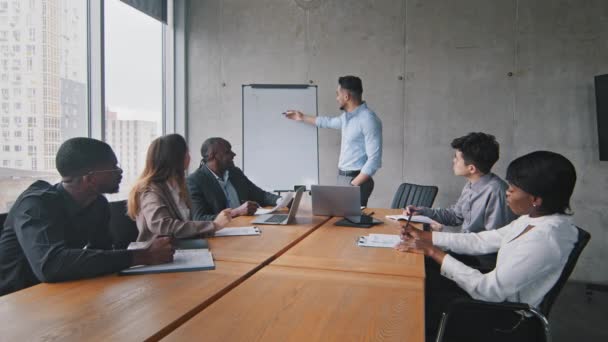 Podnikatelé rozmanitost businessteam multietnické kolegy sedí u stolu v kanceláři setkání briefing poslech zprávy arabsky hispánský podnikatel šéf psaní na bílou tabuli vysvětlující strategii — Stock video