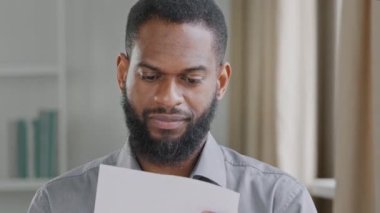 Çift ırklı, genç, yetişkin bir erkeğe mektup, banka kredisi onayı, maaş artışı, terfi bildirimi. Afrikalı adam iyi haberler okuyor, sevinçle zafere koşuyor. Beklenmedik güzel haberler.