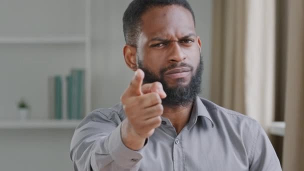 Молодой бородатый рассерженный африканский черный бизнесмен, профессиональный менеджер по персоналу, работодатель протягивает руку, показывая пальцем в камеру, осуждая угрозы работы, предупреждая обещать увольнение концепции — стоковое видео