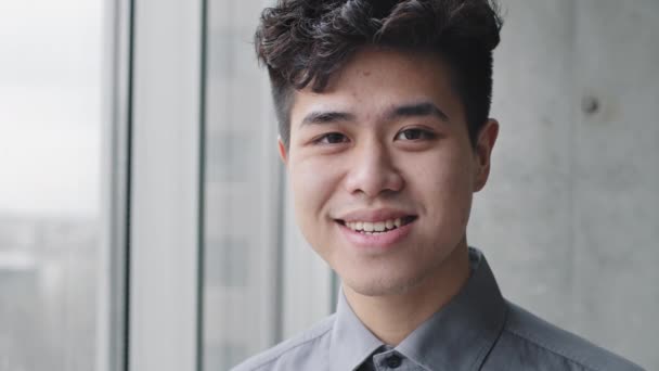 Indoor portrait asian guy student korean business man chinese manager office worker leader wears formal shirt standing near window looking at camera smiling toothy. Close-up male happy satisfied face — Stock Video