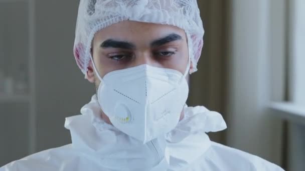 悲しい疲れアラブ人医師スペイン人医師外科医は、医療保護制服を身に着けている機器は、クリニックパンデミックでのハードワーク後に救済呼吸空気と眼鏡やマスクの呼気を離陸 — ストック動画