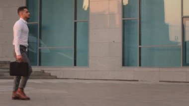 İspanyol iş adamı, patron, yönetici, resmi giysiler içindeki erkek avukat, iş görüşmesi için ofis binasının yakınındaki sokakta yürüyen evrak çantasını tutuyor.