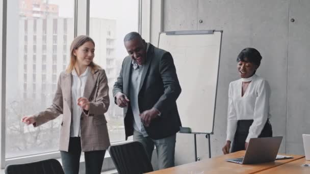 Motivado divertido diverso equipo de negocios gente bailando celebrando el éxito en la oficina regocijarse con viernes fin de semana, feliz amistoso multiracial tres compañeros de trabajo grupo divirtiéndose juntos disfrutar de danza victoria — Vídeos de Stock