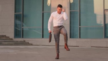 Tam boy görüşlü Arap İspanyol iş adamı yönetici elinde dizüstü bilgisayarla dışarıda durup zafer jesti yaparsa sevinç verici bir zafer kazanmış olur.