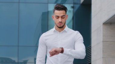 Portre, sabırsız İspanyol sakallı adam huysuz iş adamı resmi bir gömlek giyiyor dışarıda durmuş kol saatine bakıyor geç kalmaktan endişe ediyor.