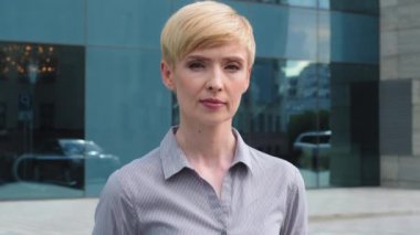 Yakın plan kadın ciddi yüz portresi Kafkas orta yaşlı iş kadını patron kısa saçlı lider resmi tişört giyiyor mutsuz bir ifade takınıyor sokakta poz verirken kameraya bakıyor