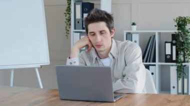 Uykusu gelen aşırı yorgun, yorgun Kafkasyalı serbest çalışan iş yerinde dizüstü bilgisayarı ofiste masanın altına düşmüş uykusuzluktan bunalmış hissediyor.