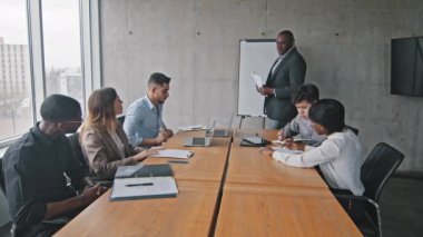 Olgun Afro-Amerikan iş adamı, elinde kağıtlar bulunan patron, çeşitli çok ırklı işletme yönetim ekibiyle yeni strateji projesi hakkında konuşmak üzere toplantı odasına girer.