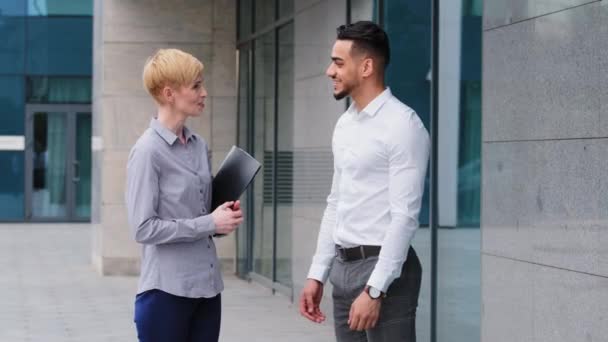 Mulher de negócios caucasiana detém pasta conversando conversa com árabe homem espanhol líder empresário apertando as mãos handshaking adeus acordo aprovação equipe trabalho união de pé perto de construção ao ar livre — Vídeo de Stock