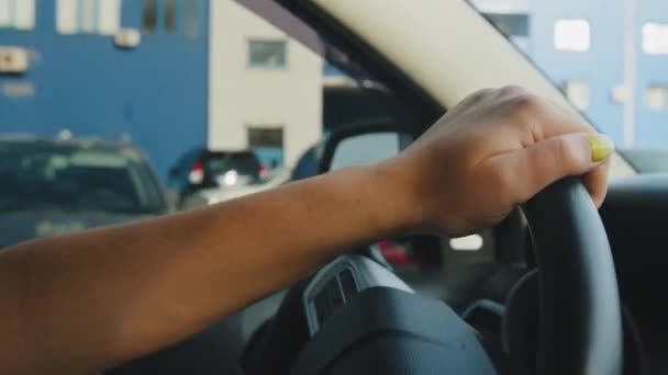 Närbild unga kaukasiska kvinnliga händer på svart fordon ratt kör lyx bil på gatan på vägen. Oigenkännlig kvinna förare i bil i motorväg bakgrund av stadstrafik beskuren vy — Stockvideo