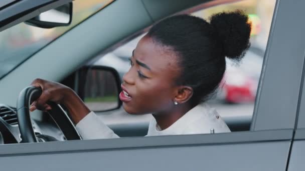 Młody afro amerykański kierowca dziewczyna zestresowany afrykański etniczne kobieta siedzi w samochodzie w korku krzycząc przysięga wściekły z powolnym transportem na drodze emocjonalnie macha rękami z problemami z jazdy — Wideo stockowe