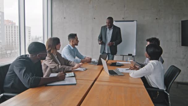 Grupo de equipe de negócios multirracial diversos parceiros colegas multiétnicos sentados à mesa na empresa de escritório na reunião brainstorm ouvindo palestra apresentação de líder chefe masculino africano maduro — Vídeo de Stock