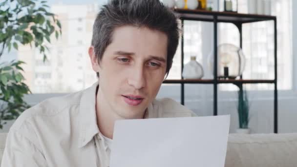 Cropped shot caucasian pensive male business man sitting on sofa at home office receiving letter notice notification announcement from bank renouncement failure refusal feeling worried reads bad news — Stock Video