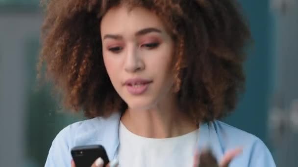 Retrato rizado mujer afro africano americano mixta chica joven modelo femenino estudiante usuario celebración de teléfono móvil habla en línea video chat conferencias con teléfono inteligente habla emocionalmente gritos disgustado — Vídeos de Stock