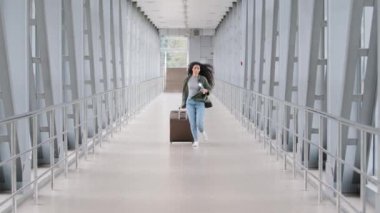 Genç İspanyol kadın kıvırcık esmer kız valizli yolcu yolcu havaalanında tren bileti ve pasaportuyla aceleyle havaalanına gidiyor.